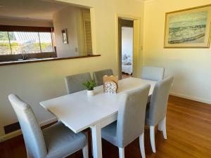 une salle à manger avec une table et des chaises blanches dans l'établissement Home in Brighton, à Melbourne