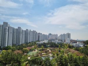 a city skyline with tall buildings and a park at Hwamyeong Sky Hotel in Busan