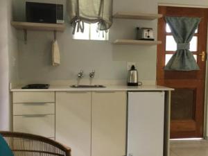 a kitchen with white cabinets and a sink and a window at Incwala Lodge in Waterval Boven