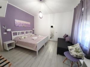 sypialnia z białym łóżkiem i fioletową ścianą w obiekcie B&B Capo al Piano w mieście Marciana Marina
