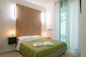 sypialnia z zielonym łóżkiem i ręcznikami w obiekcie B&B Al Parco w Weronie