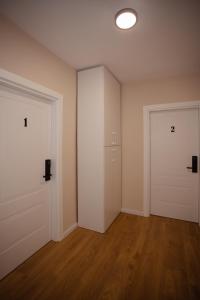 ein leeres Zimmer mit zwei weißen Türen und Holzböden in der Unterkunft City Center Studio Apartments in Shkodra