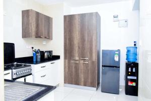 a kitchen with wooden cabinets and a stainless steel refrigerator at Amalia Apartments Syokimau in Machakos