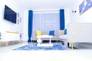a living room with blue curtains and a couch at Amalia Apartments Syokimau in Machakos