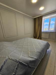 a bedroom with a large bed in front of a window at Двухкомнатная квартира на Ауезова in Kokshetau