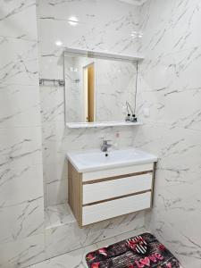 uma casa de banho branca com um lavatório e um espelho em Двухкомнатная квартира на Ауезова em Kokshetau