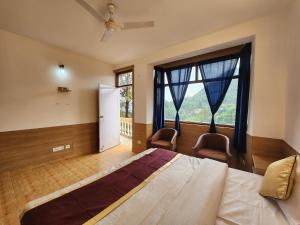 a bedroom with a bed with two chairs and a large window at Villa Kartina by the Hillstay in Bhowāli