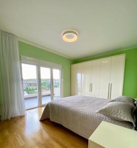 a green bedroom with a bed and a window at Krimovica Sunset in Krimovice
