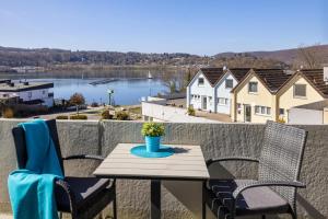 a table and chairs on a balcony with a view of the water at Seeblick genießen in schöner FeWo am Edersee in Scheid