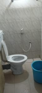 La salle de bains est pourvue de toilettes et d'un seau bleu. dans l'établissement Misty Meadows, à Ooty