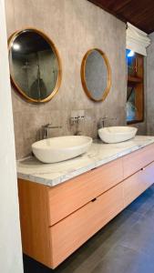 two sinks in a bathroom with two mirrors at Tegal Sari Accommodation Ubud in Ubud