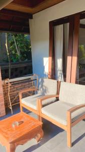 a porch with two chairs and a coffee table at Tegal Sari Accommodation Ubud in Ubud