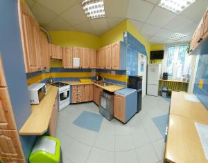 a kitchen with wooden cabinets and yellow and blue walls at Youth Hostel Podlasie in Białystok
