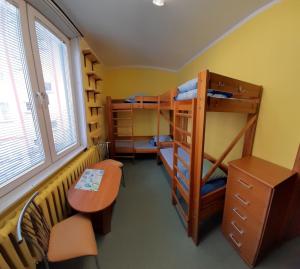 a room with bunk beds and a desk and a table at Youth Hostel Podlasie in Białystok