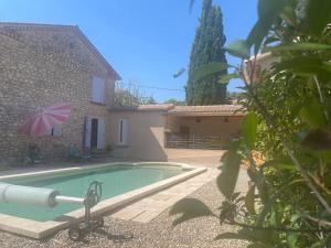 a pool in front of a house with an umbrella at lagalerie84 in Saint-Saturnin-dʼApt
