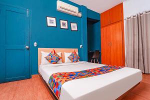 a bedroom with a bed with a blue wall at FabExpress Harma Residency in Chennai