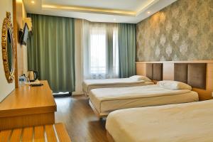 a hotel room with three beds with green curtains at Start Hotel in Antalya