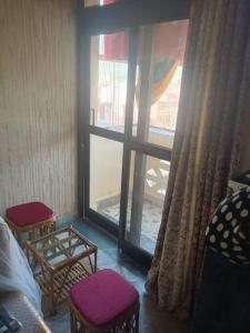 um quarto com uma grande janela com 2 cadeiras e uma mesa em My Uttrakhand Experiences em Haridwar