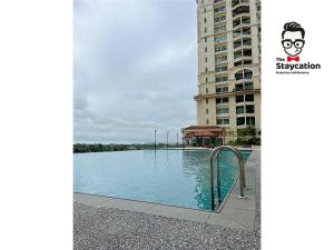 una piscina di fronte a un edificio alto di Staycation Homestay 19 Riverine Petanak Apartment a Kuching