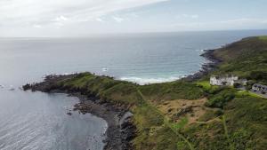an aerial view of a house on a cliff next to the ocean at Journeys End with surrounding Sea views in Coverack
