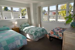 1 dormitorio con 2 camas y 2 ventanas en Comfortable Home, Big Backyard en Rotorua