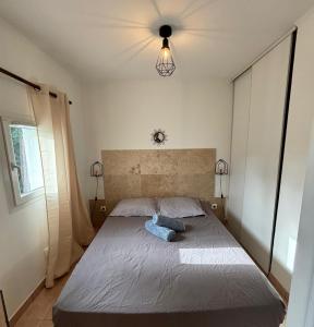 Un dormitorio con una cama con una almohada azul. en Charmante maisonnette situé au calme proche d'Ajaccio. en Afa