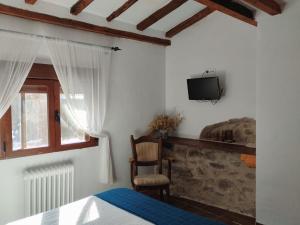 a bedroom with a bed and a tv on the wall at Hostal Refugio De Gredos in Navarredonda de Gredos