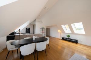 eine Küche und ein Esszimmer mit einem schwarzen Tisch und weißen Stühlen in der Unterkunft Luxury Penthouse Schönbrunn in Wien