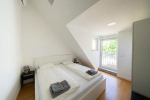 a white bedroom with a bed and a window at Luxury Penthouse Schönbrunn in Vienna