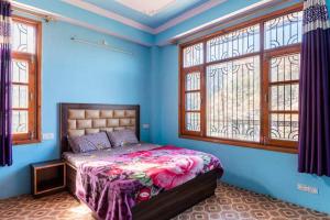 a bedroom with a bed with blue walls and windows at Indu BNB Shimla in Shimla