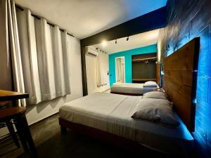 a bedroom with two beds and a blue wall at Zyan Rooms in Villahermosa