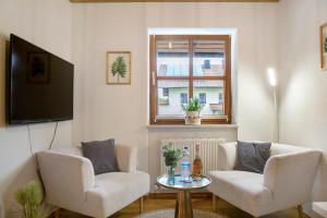 ein Wohnzimmer mit 2 Stühlen, einem Tisch und einem Fenster in der Unterkunft Schönauer Hof - Wohnung Max Josef in Passau