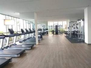 a gym with a row of treadmills and machines at gold coast pik BEACH ROOM 1br netflix wifi sofa bed in Jakarta