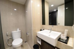 uma casa de banho com um WC branco e um lavatório. em HORU HOTEL MANGGA DUA SQUARE em Jacarta