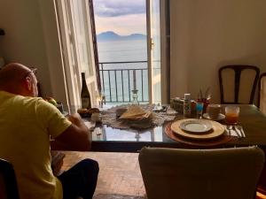 einem Mann, der an einem Tisch mit Meerblick sitzt in der Unterkunft B&B Vista Mare in Neapel