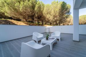 a room with white chairs and a table and trees at Apartment Nascer do Sol in Aljezur