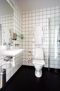a white bathroom with a toilet and a sink at Kviberg Park Hotel & Conference in Gothenburg