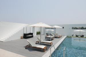 River View Pathum Hotel and Residence في محافظة باثوم ثاني: حمام سباحة به كراسي ومظلات على سطح السفينة