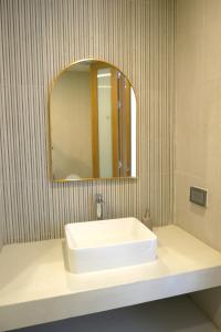uma casa de banho com um lavatório branco e um espelho. em River View Pathum Hotel and Residence em Pathum Thani