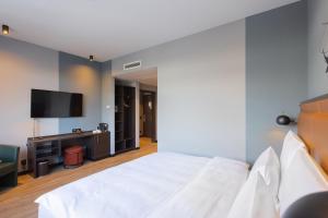 1 dormitorio con 1 cama blanca y TV de pantalla plana en TITANIC Comfort Kurfürstendamm, en Berlín