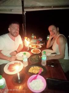 Ein Mann und eine Frau sitzen an einem Tisch mit Essen in der Unterkunft Cakrawala in Kumai