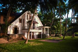 a white house with palm trees in front of it at Baywatch by Grha - A Picturesque Beachfront Villa in Kozhikode