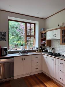 a large kitchen with white cabinets and a window at Gorgeous Villa, 7 minutes from Airport in Christchurch