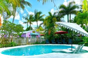 a swimming pool with two chairs and an umbrella at Tropical Nola Studio Vacation Rental in West Palm Beach