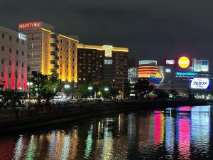 a city at night with a river and buildings at FukuokaKoryou GuestHouse in Fukuoka