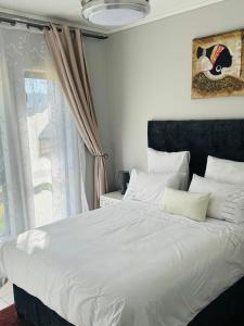 um quarto com uma grande cama branca e uma janela em Lakhe Lethu Apartment: Green Valley Estate em Nelspruit