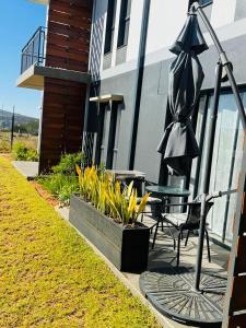 a patio with a table and an umbrella and flowers at Lakhe Lethu Apartment: Green Valley Estate in Nelspruit
