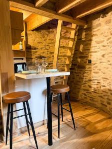een keuken met een tafel en 2 krukken in een kamer bij Le Four' Nid in La Terrasse-sur-Dorlay