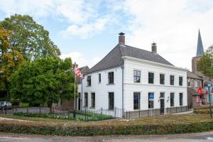 un edificio blanco con una bandera delante de él en Logement 1818 en Bakel