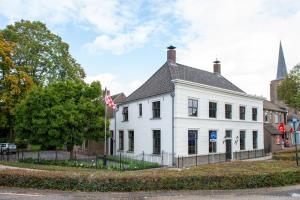 a white building with a flag in front of it at Logement 1818 in Bakel
